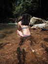 Sexy asian woman in bikini in the stream water playing with wild fishes. transparent water in waterfall with many natural fish. Th Royalty Free Stock Photo