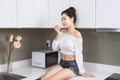 Sexy Asian woman eating apple while sitting in kitchen Royalty Free Stock Photo