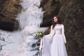 bride with a wedding bouquet of flowers on a background with a glacier and mountains Royalty Free Stock Photo