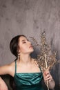 Sexy attractive brunette woman in elegant green aquamarine dress with artificial branch with sparkly sequins. beautiful sensual