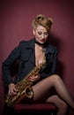 attractive woman with saxophone posing on red background. Young sensual blonde playing sax. Musical instrument, jazz Royalty Free Stock Photo