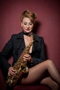 attractive woman with saxophone posing on red background. Young sensual blonde playing sax. Musical instrument, jazz Royalty Free Stock Photo