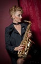 attractive woman with saxophone posing on red background. Young sensual blonde playing sax. Musical instrument, jazz Royalty Free Stock Photo