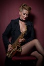 attractive woman with saxophone posing on red background. Young sensual blonde playing sax. Musical instrument, jazz Royalty Free Stock Photo