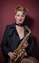 attractive woman with saxophone posing on red background. Young sensual blonde playing sax. Musical instrument, jazz Royalty Free Stock Photo