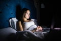Attractive Young Woman Relaxing in Bed With Laptop Computer. Woman working on laptop in the night in bed. Woman chating in la