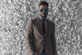 Sexy bearded guy with retro sunglasses posing in front of tinfoil background Royalty Free Stock Photo