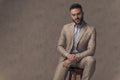 Sexy bearded man in suit with undone shirt sitting on wooden chair