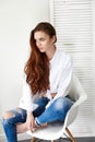 beautiful girl in jeans white shirt sitting on a chair. Gorgeous long hair and charming eyes young woman. Business lady Royalty Free Stock Photo