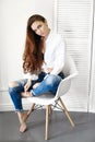 beautiful girl in jeans white shirt sitting on a chair. Gorgeous long hair and charming eyes young woman. Business lady Royalty Free Stock Photo