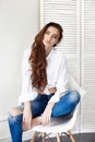 beautiful girl in jeans white shirt sitting on a chair. Gorgeous long hair and charming eyes young woman. Business lady Royalty Free Stock Photo