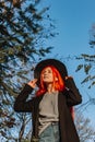 Sexy beautiful redhead girl with long, strong and thick hair in a black hat and coat. Perfect woman portrait. Gorgeous deep blue Royalty Free Stock Photo