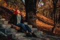 Sexy beautiful redhead girl with magnificent long hair. Ukulele playing, sitting on the steps in the park. Perfect woman portrait