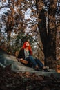 Sexy beautiful redhead girl with magnificent long hair. Ukulele playing, sitting on the steps in the park. Perfect woman portrait Royalty Free Stock Photo