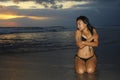 and beautiful young Asian woman relaxing playful at sunset beach kneeling on water Royalty Free Stock Photo