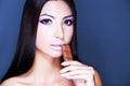 Sexy Beauty Woman Portrait. Professional Holiday Make up for Brunette. Beautiful Fashion Model Girl eating chocolate. Long Hair. Royalty Free Stock Photo