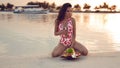 Sexy bikini woman with fruits bowl Enjoying Beautiful Sunset on Tropical Beach. Brunette model with long healthy wavy hair relax Royalty Free Stock Photo