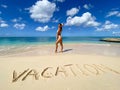 Sexy bikini woman playful on paradise tropical beach with inscription on sand. Travel and vacation concept