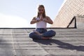 Sexy blonde girl meditates in solitude on the roof on a sunny day