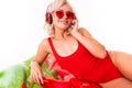 Sexy blonde girl in a red swimsuit and sunglasses lies on a swimming mattress and listens to music on headphones Royalty Free Stock Photo