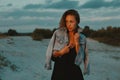 blonde haired young woman posing in sands of desert lit by red setting sun light