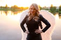 sexy blonde woman in black leather jacket and shorts with white angel wings. demon or angel in hell or heaven. sunset Royalty Free Stock Photo