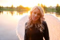 sexy blonde woman in black leather jacket and shorts with white angel wings. demon or angel in hell or heaven. sunset Royalty Free Stock Photo