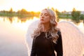 sexy blonde woman in black leather jacket and shorts with white angel wings. demon or angel in hell or heaven. sunset Royalty Free Stock Photo