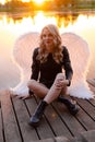 sexy blonde woman in black leather jacket and shorts with white angel wings. demon or angel in hell or heaven. sunset Royalty Free Stock Photo