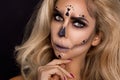 blonde woman in Halloween makeup and leather outfit on a black background in the studio. Skeleton, monster and witch. Royalty Free Stock Photo