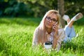 Sexy blonde woman talking on the mobile phone and lying on meadow