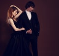 Sexy bright foxy hairstyle female woman in fashion green dress posing with handsome man in black suit clothing on dark shadow