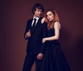 Sexy bright redSexy redheaded hairstyle female woman in fashion black long skirt dress hugging her handsome man in black suit Royalty Free Stock Photo