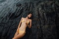 brunette in bikini lies on a large rock on ocean coast