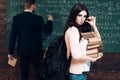 brunette female student holding her glasses while carrying pile of books. Young college girl in pink cardigan Royalty Free Stock Photo