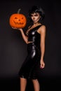 brunette woman in Halloween makeup and lingerie hold a pumpkin on a black background in the studio. Make-up skeleton, monster Royalty Free Stock Photo