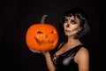 brunette woman in Halloween makeup and lingerie hold a pumpkin on a black background in the studio. Make-up skeleton, monster Royalty Free Stock Photo