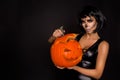 brunette woman in Halloween makeup and lingerie hold a pumpkin on a black background in the studio. Make-up skeleton, monster Royalty Free Stock Photo