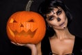 brunette woman in Halloween makeup and lingerie hold a pumpkin on a black background in the studio. Make-up skeleton, monster Royalty Free Stock Photo