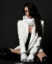 Sexy brunette pretty woman model in high boots, jacket and frill collar sitting on stool looking at camera Royalty Free Stock Photo