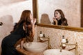 Sexy brunette woman in black dress sitting on the washbasin Royalty Free Stock Photo