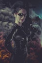 brunette woman in latex jumpsuit with heavy gun over smoke Royalty Free Stock Photo