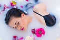 brunette woman relaxing in a hot bath with flowers