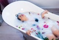 brunette woman relaxing in hot milk bath with flowers Royalty Free Stock Photo