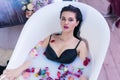 brunette woman relaxing in hot milk bath with flowers Royalty Free Stock Photo