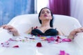 brunette woman relaxing in hot milk bath with flowers Royalty Free Stock Photo