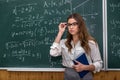 Sexy caucasian female teacher against blackboard with mathematical formulas in classroom Royalty Free Stock Photo