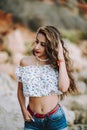 Sexy woman in short jeans and an open shirt showing a fit belly standing with an cliff behind Royalty Free Stock Photo