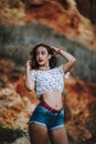 Sexy woman in short jeans and an open shirt showing a fit belly standing with a cliff behind Royalty Free Stock Photo