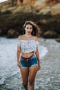 Sexy caucasian woman in short jeans and an open shirt showing a fit belly walking along a coastline Royalty Free Stock Photo